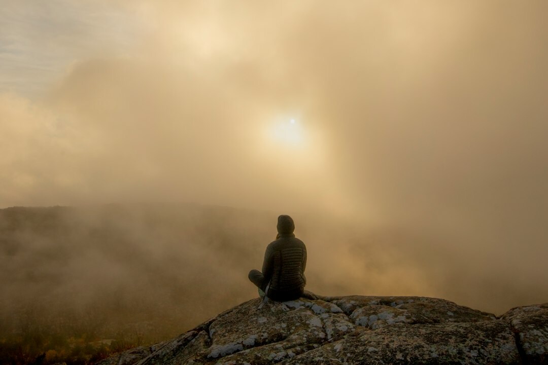person meditating at sunrise